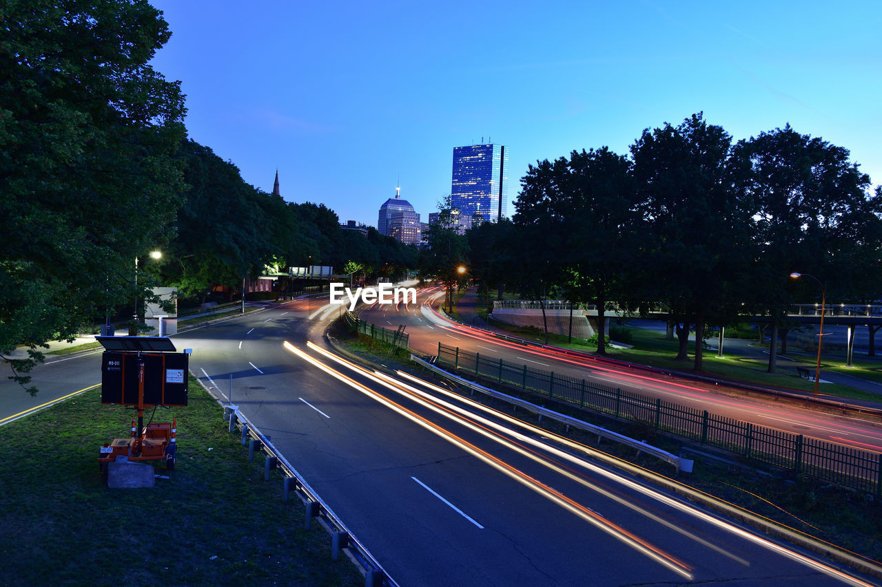 Light trails on road in city against sky