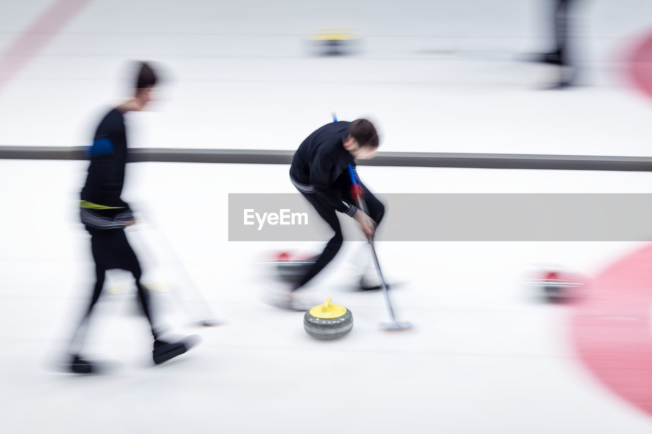 Blurred motion of people playing curling