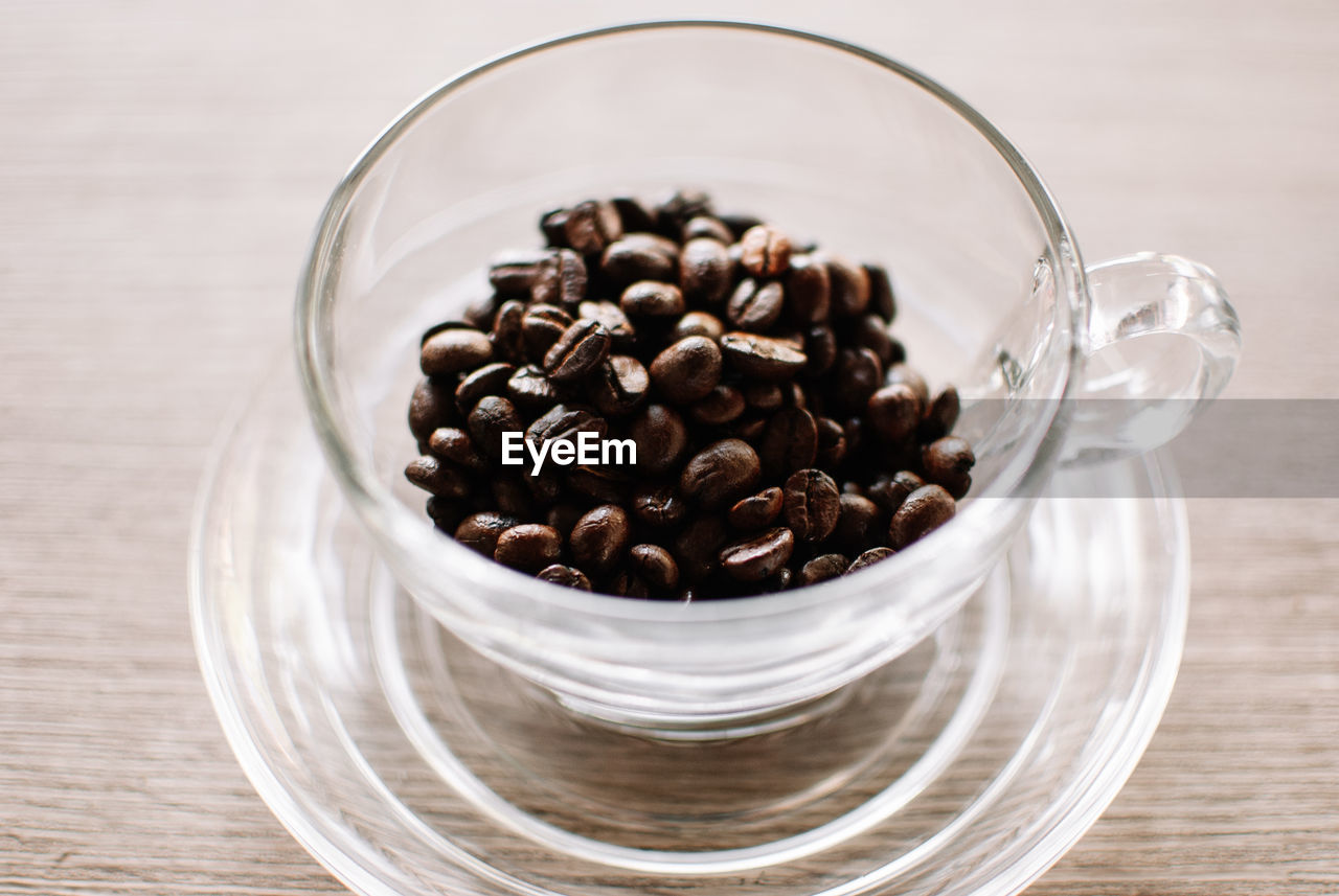 CLOSE-UP OF COFFEE BEANS IN GLASS ON TABLE