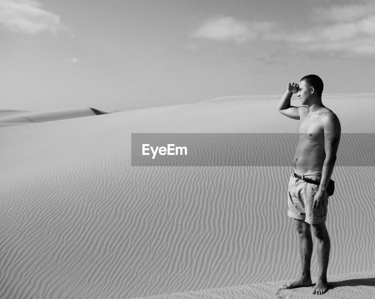 Full length of shirtless man standing at beach against sky