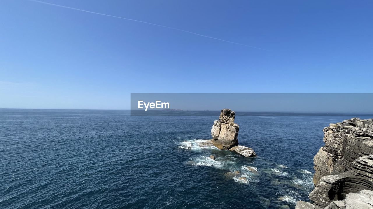 ROCKS IN SEA AGAINST BLUE SKY