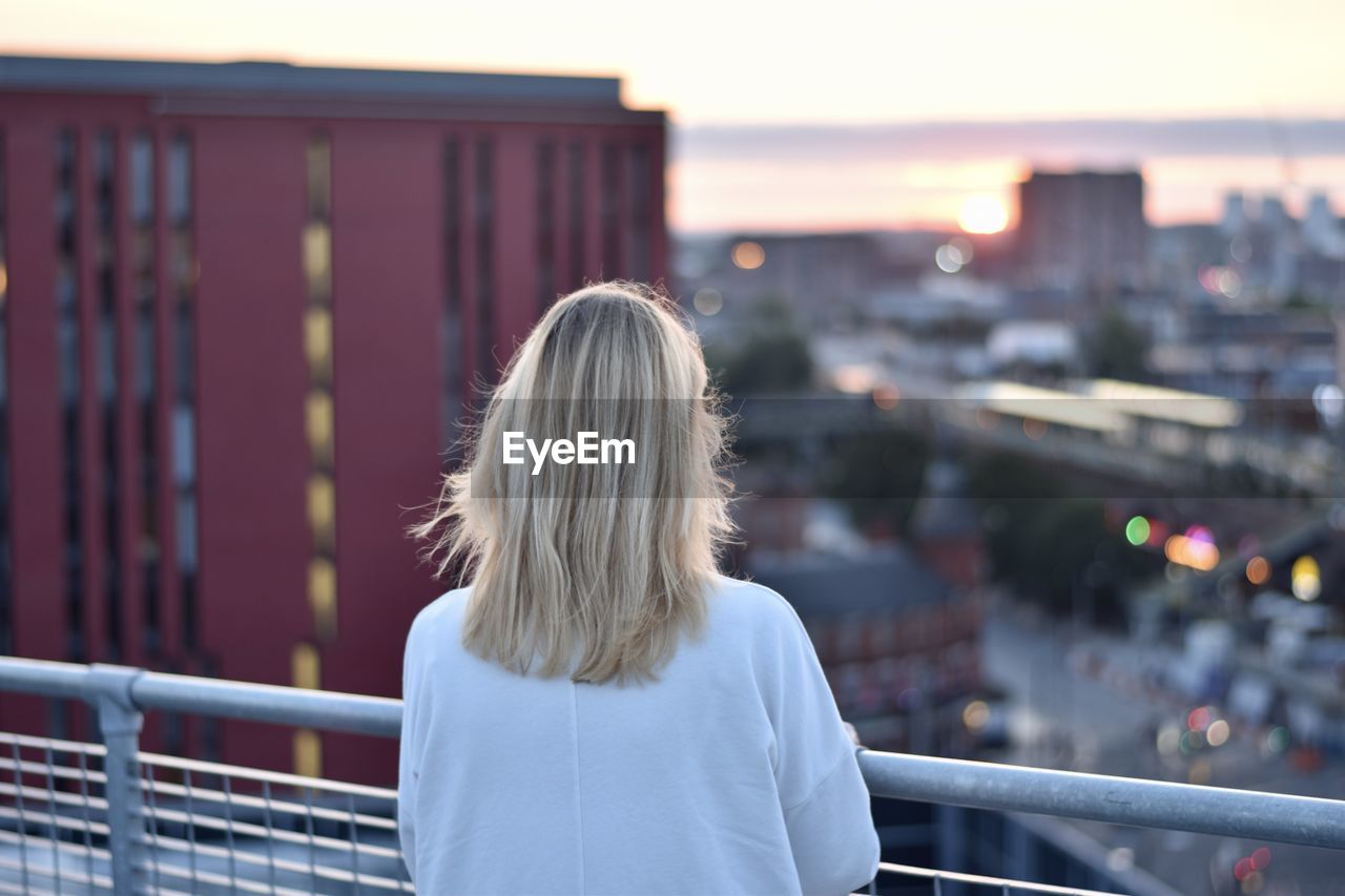 Rear view of woman standing against railing in city