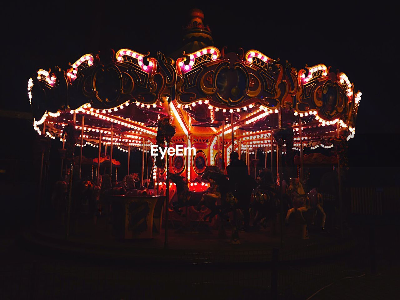 Illuminated carousel in amusement park at night