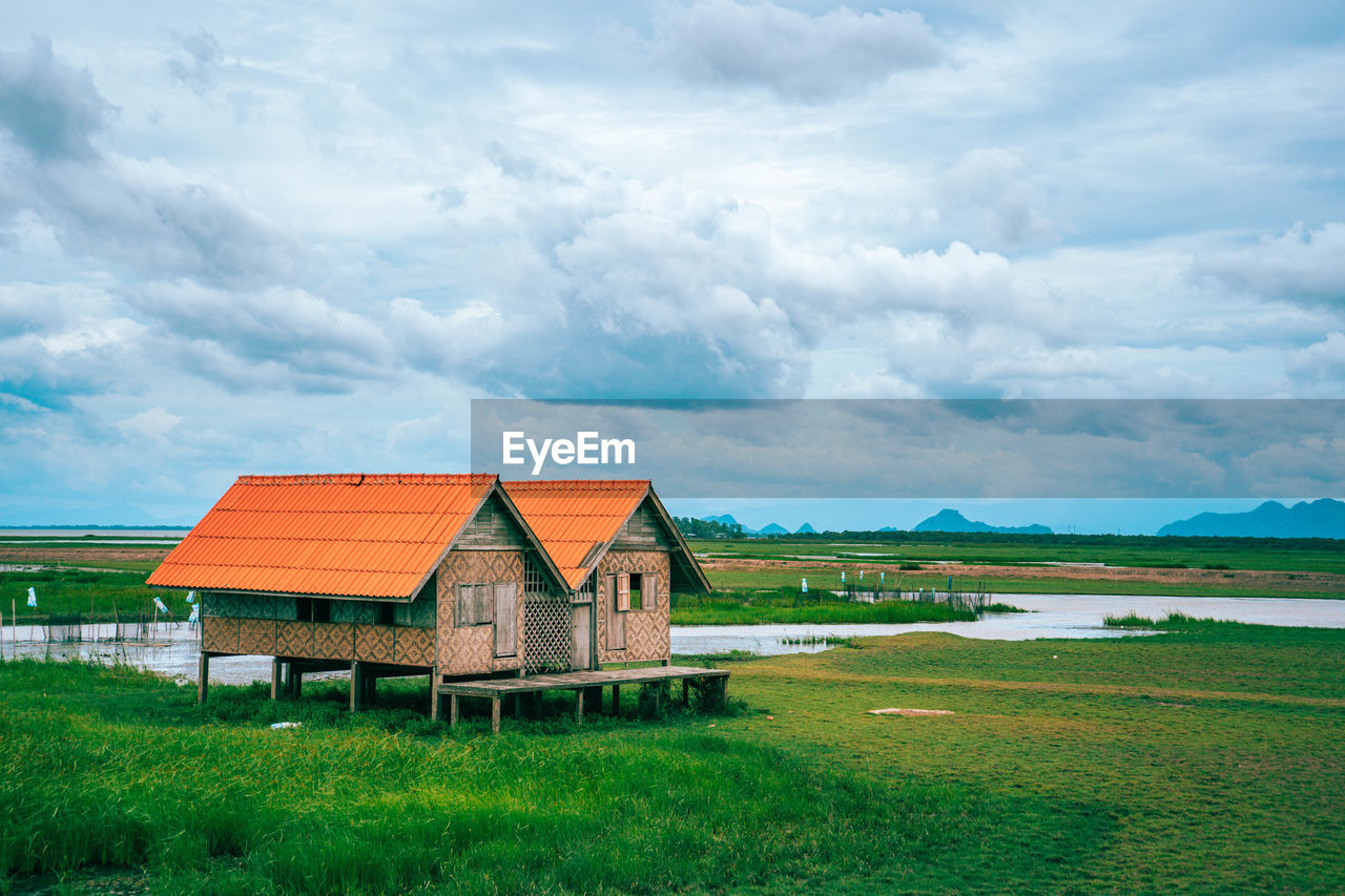 HOUSES ON FIELD AGAINST SKY