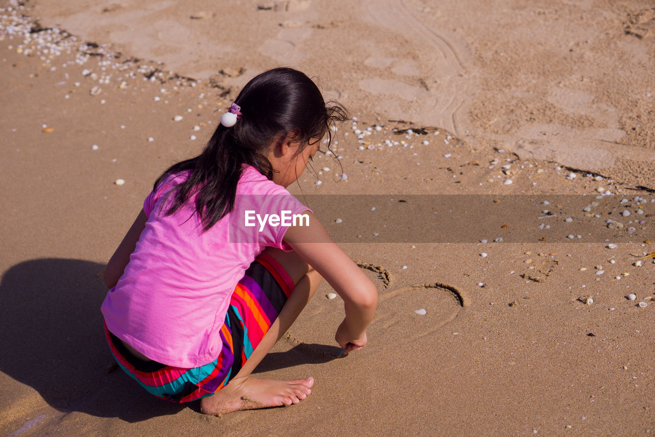 HIGH ANGLE VIEW OF WOMAN SITTING ON BEACH