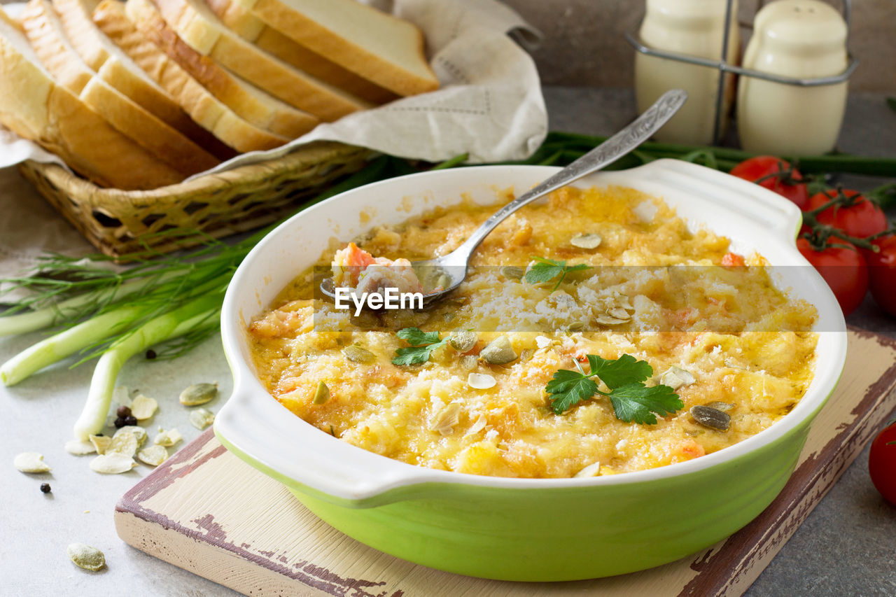 Casserole crumble with red fish, white bread and cheese on stone or slate background. 