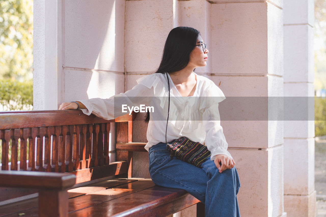 Woman looking away while sitting on bench