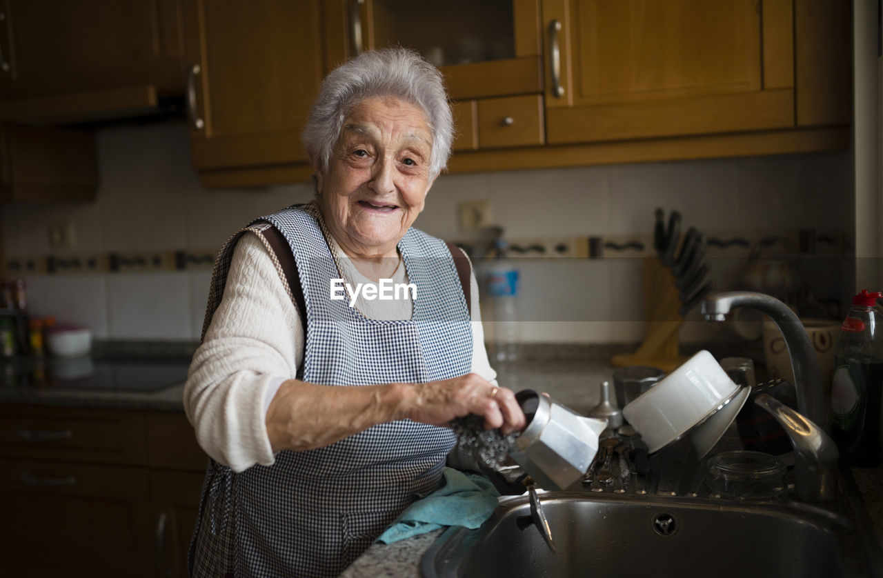 Senior woman washing dishes in kitchen