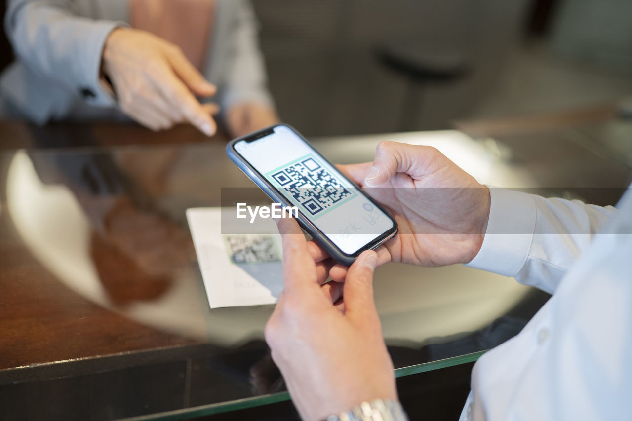 Mature man scanning qr code at hotel reception