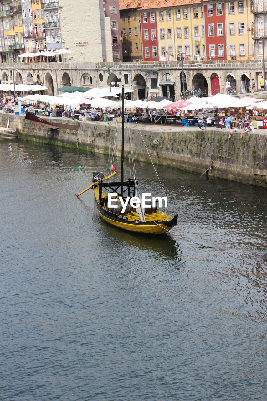 BOATS SAILING IN RIVER IN CITY