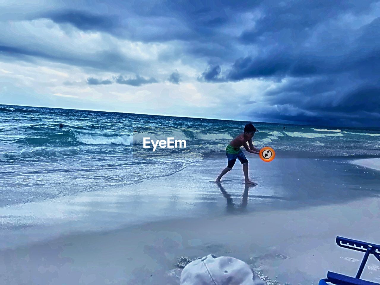 MAN CYCLING ON BEACH AGAINST SKY