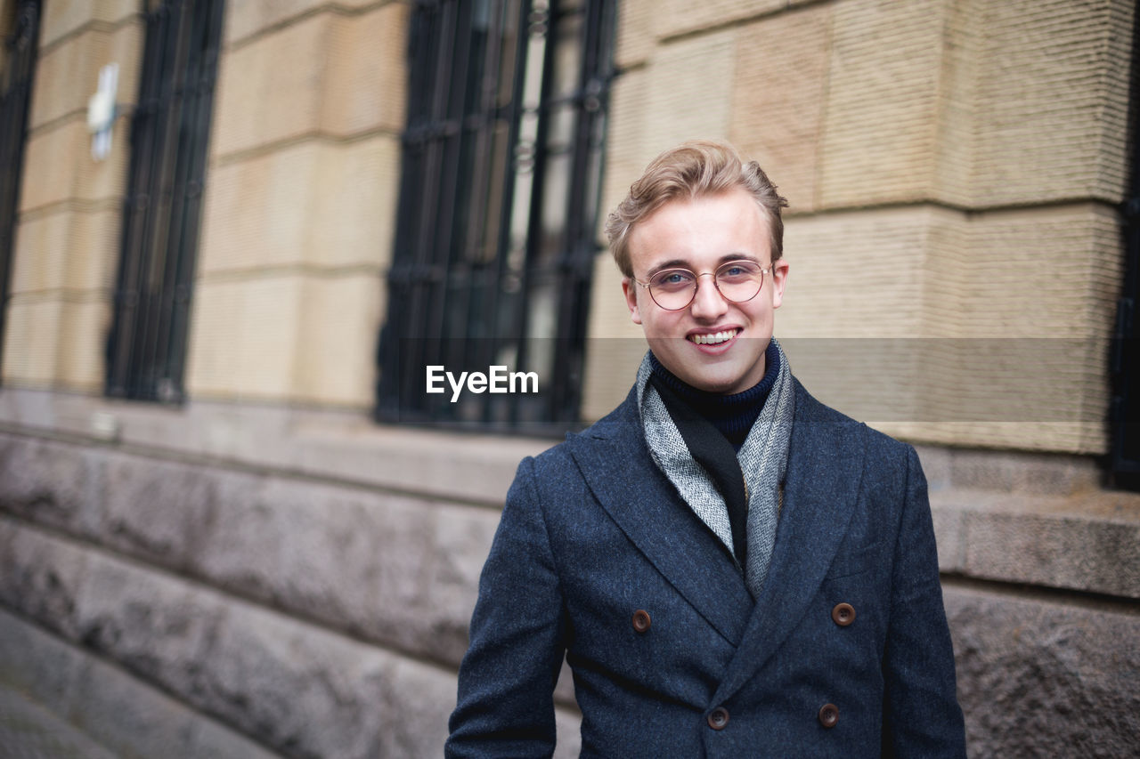 Portrait of young man standing against building