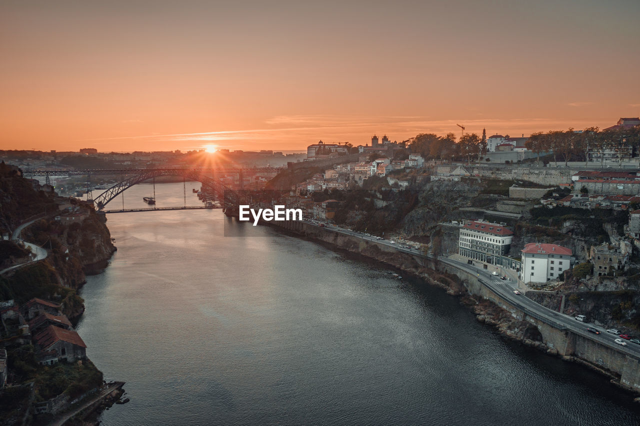 River amidst buildings against sky during sunset