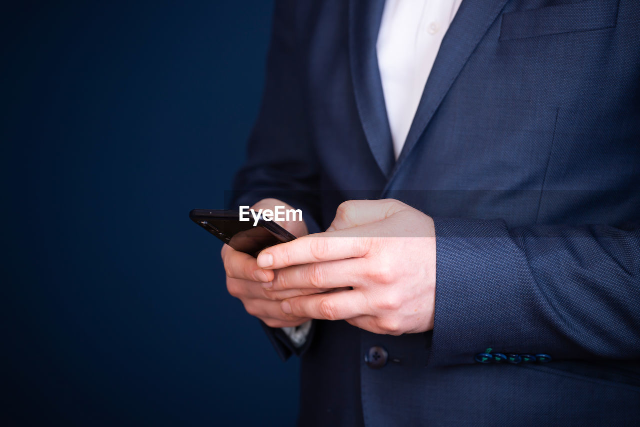 Midsection of businessman using mobile phone