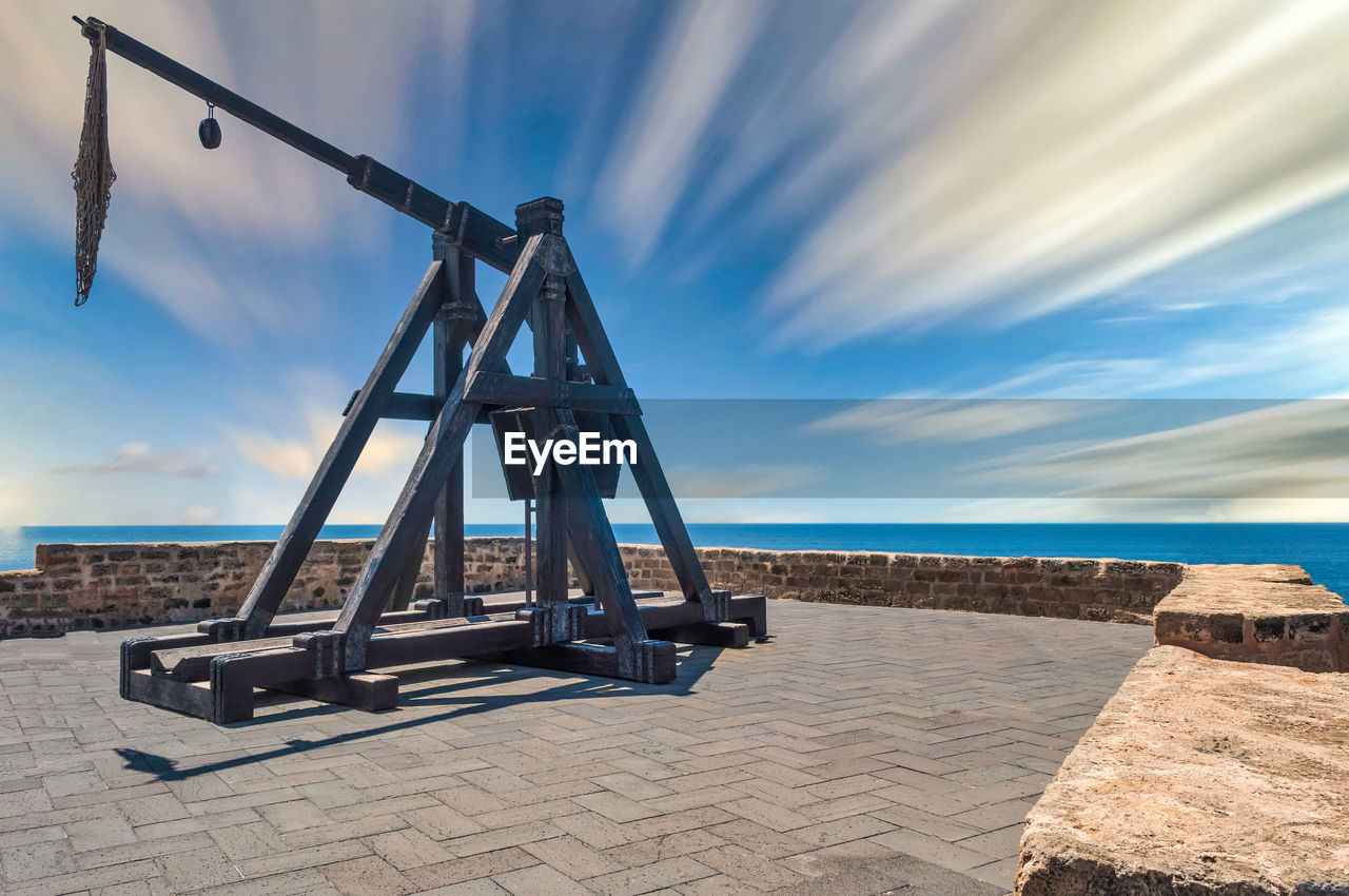 Ancient catapult on the ramparts of alghero in a sunny day of spring with long exposure clouds