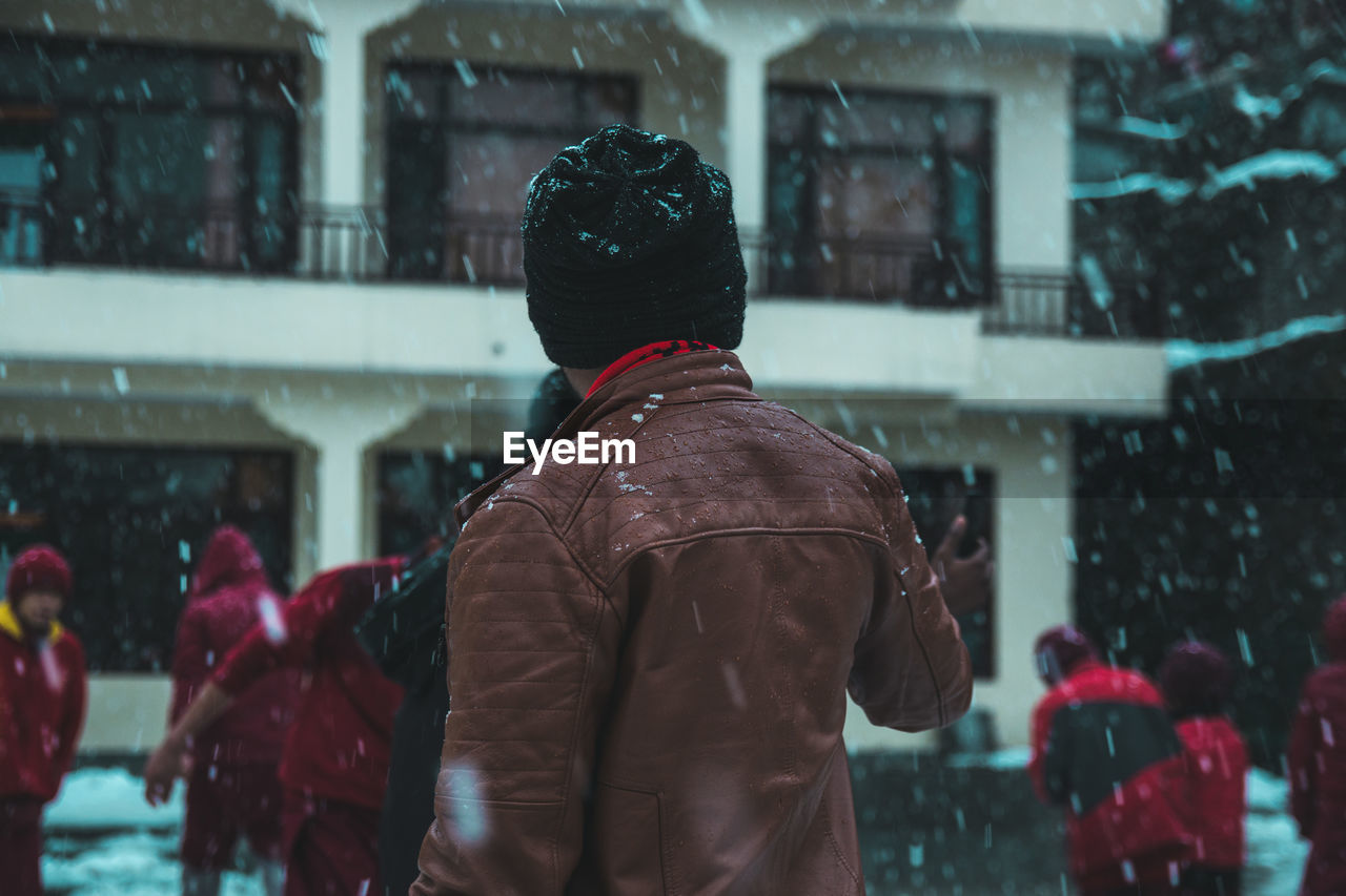 REAR VIEW OF MAN STANDING IN SNOW