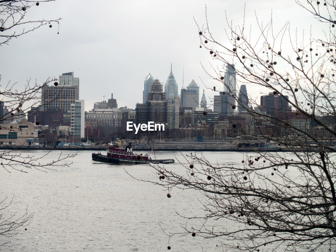 Ferry sailing in river by city skyline against clear sky