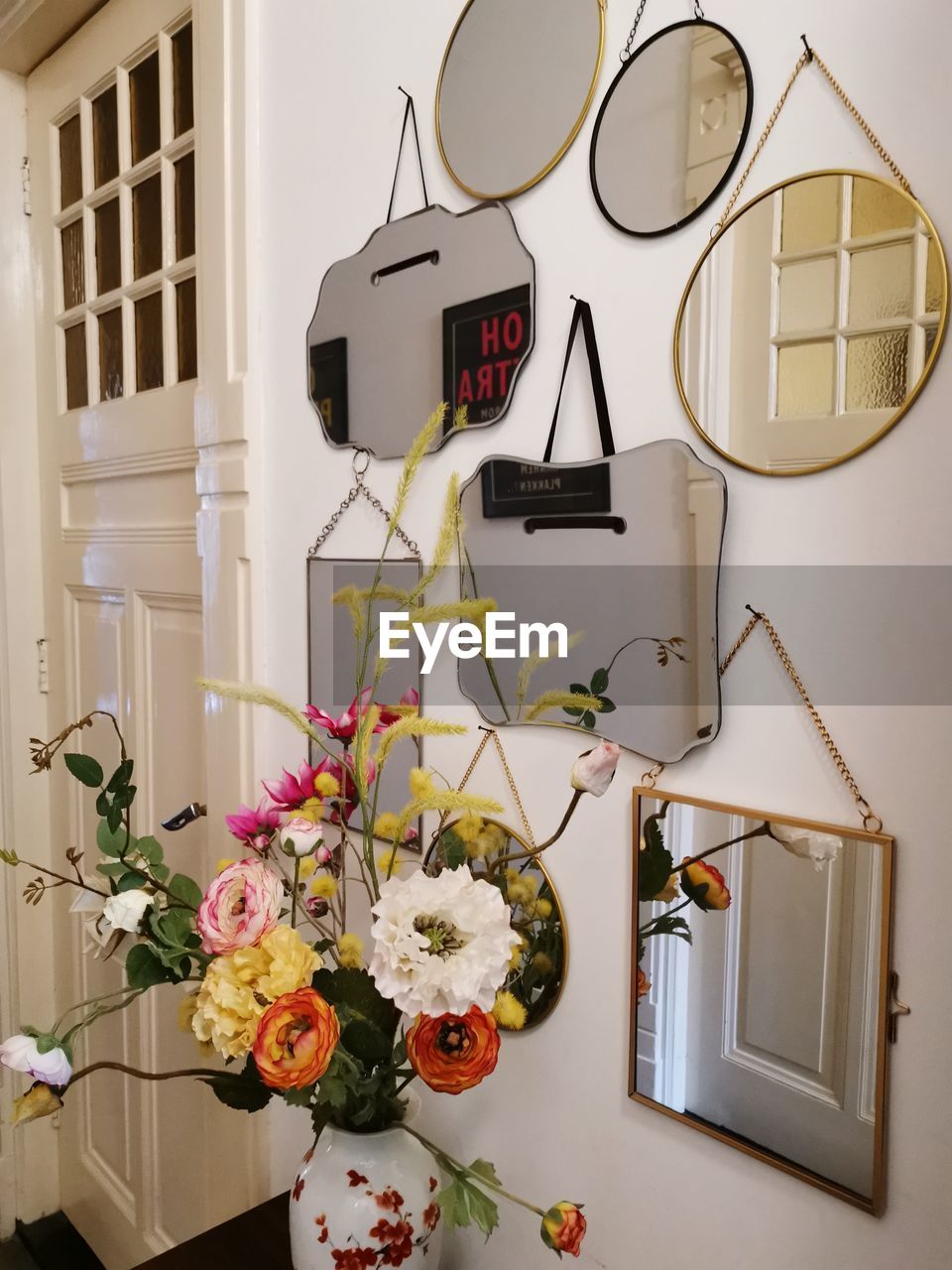 Flower vase on table against wall with mirrors at home