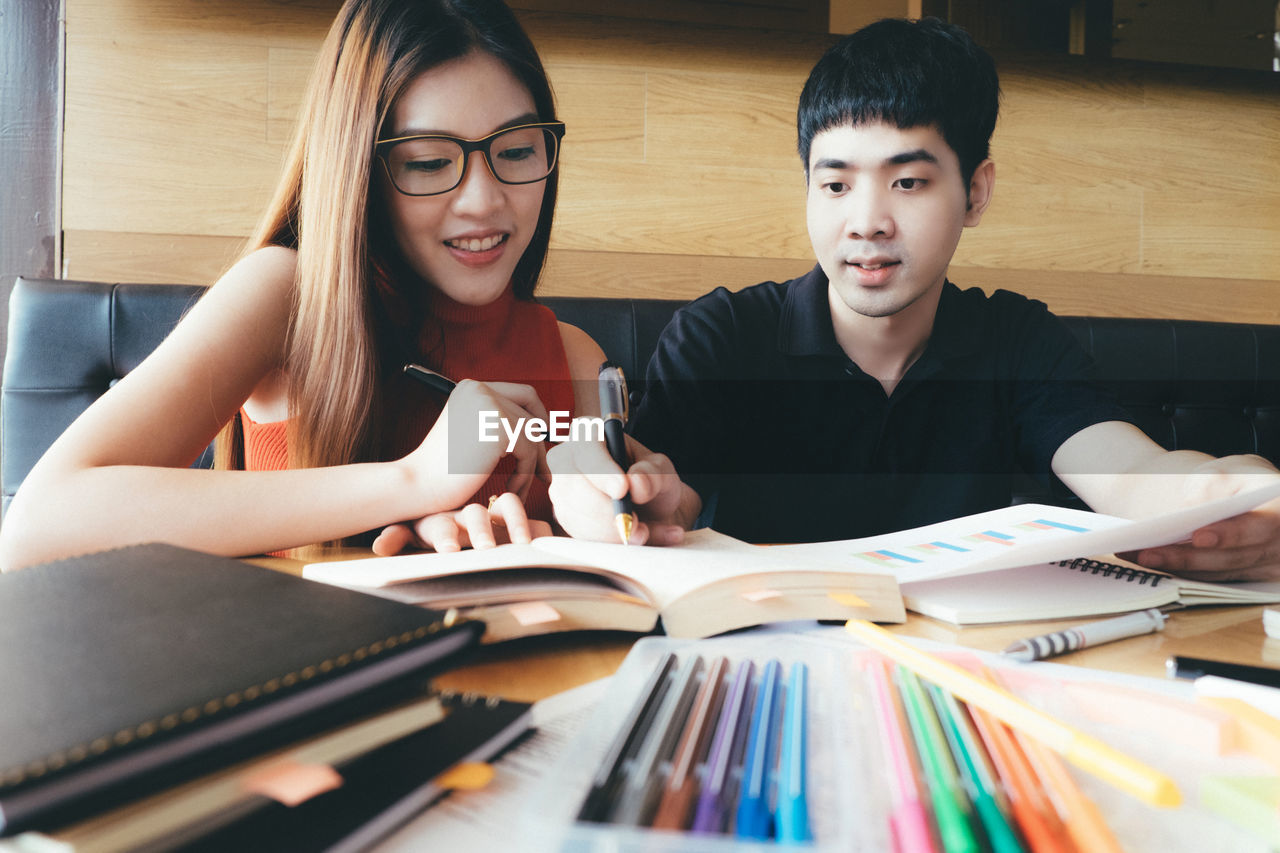 Friends studying together while sitting at table