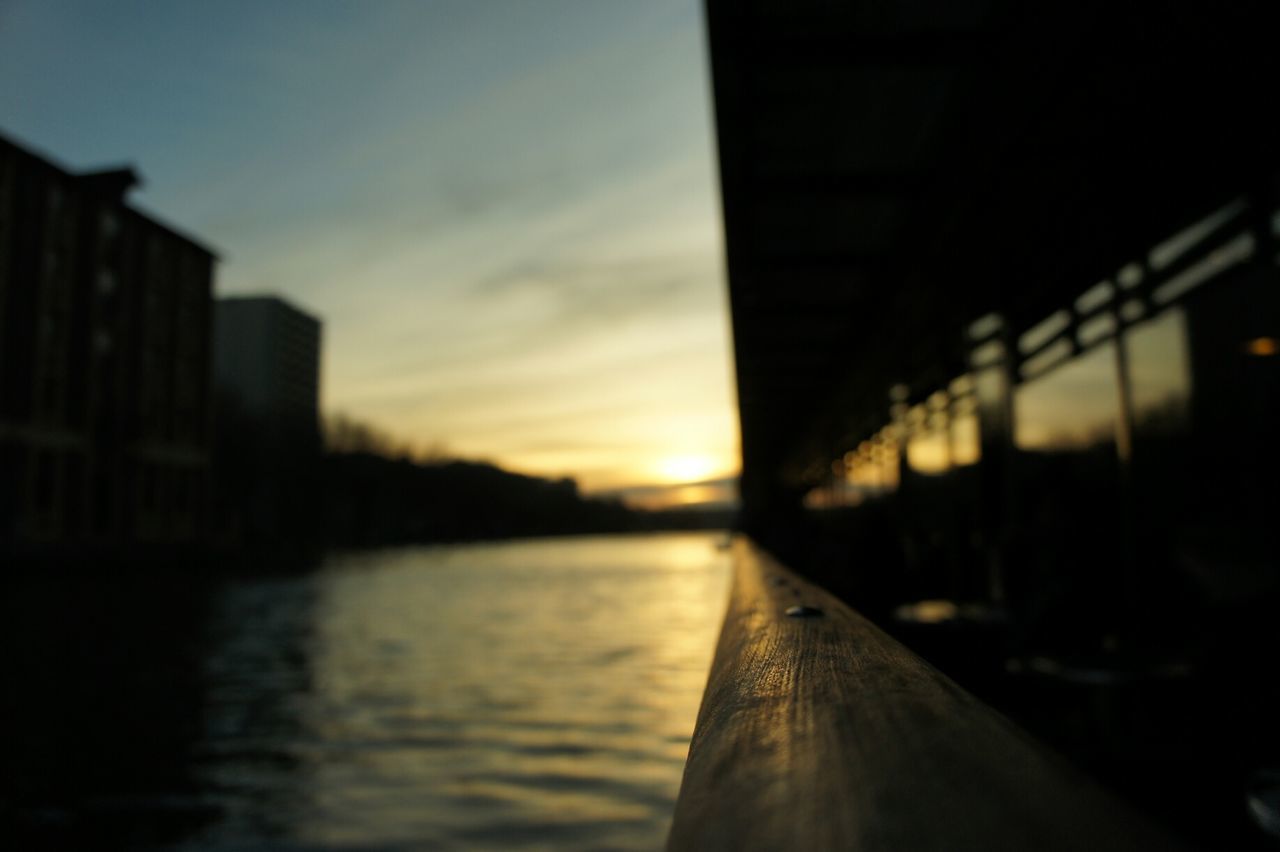 Close-up of railing by river against sky