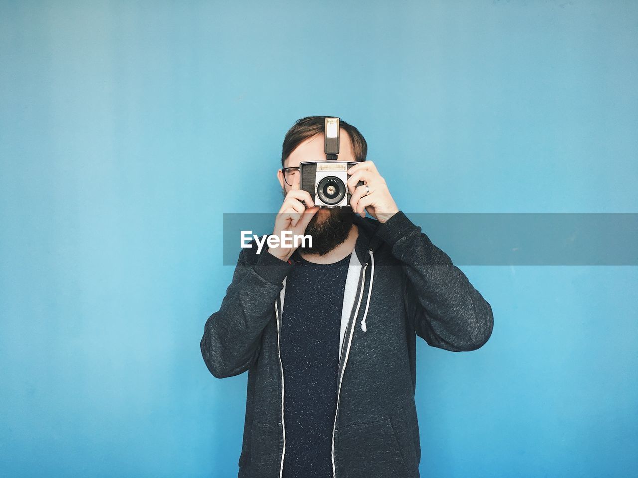 Portrait of a man using analog camera against blue background