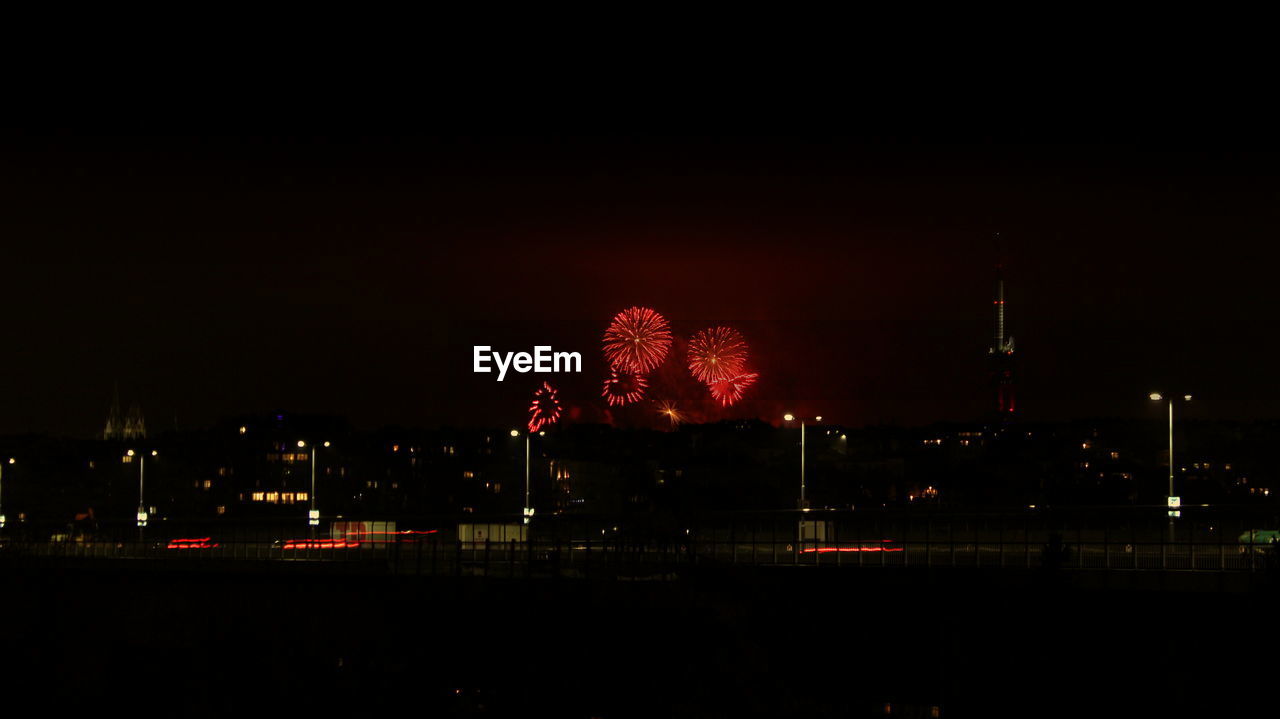 Firework display in city against sky at night