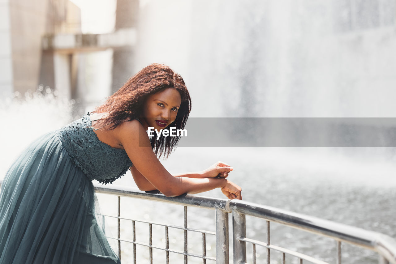 Portrait of beautiful african american woman smiling and looking away at park during sunset. 