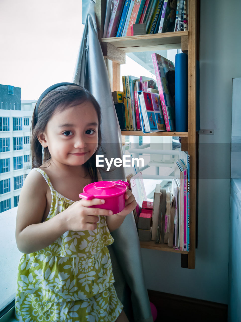 Toddler girl playing toy kitchen at home.