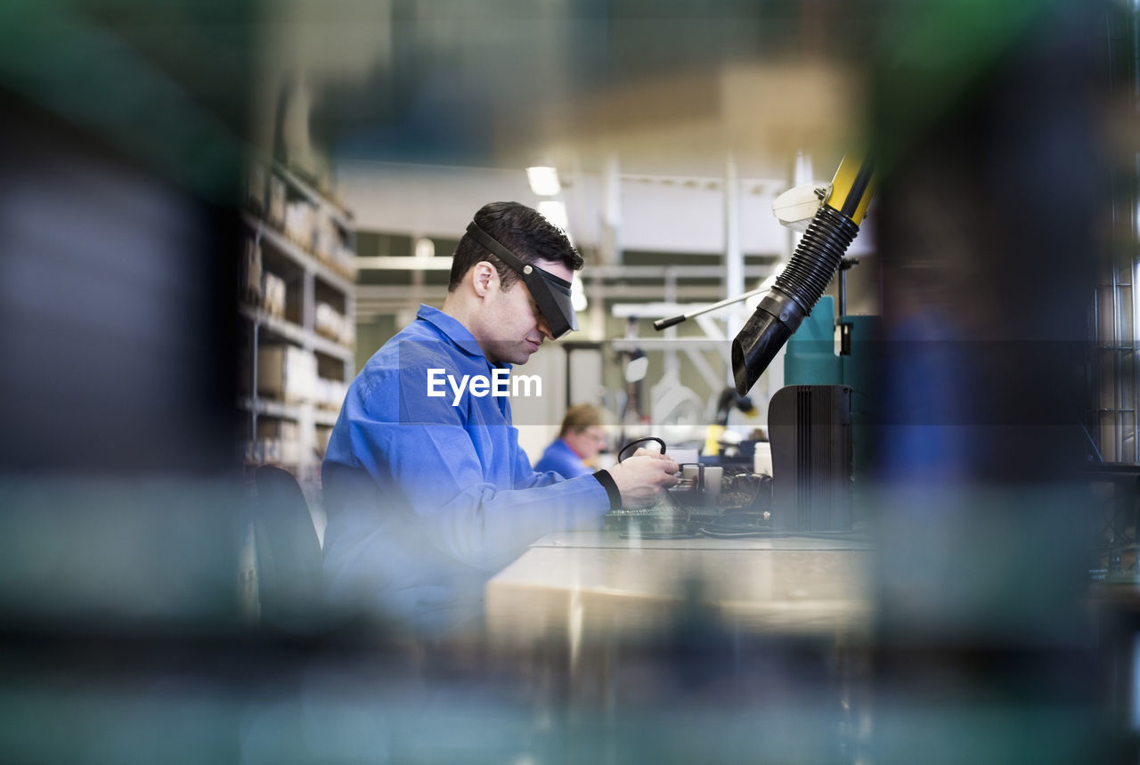 Side view of male technician wearing protective eyewear working in industry
