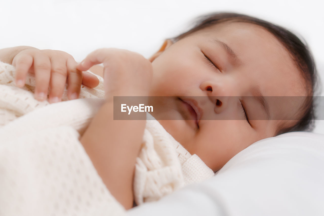 CLOSE-UP PORTRAIT OF BABY LYING ON BED