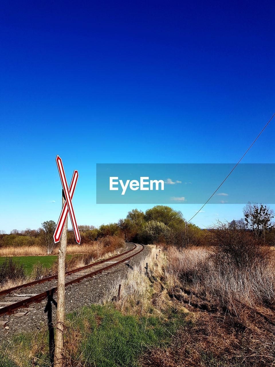 Electricity pylon by trees against blue sky