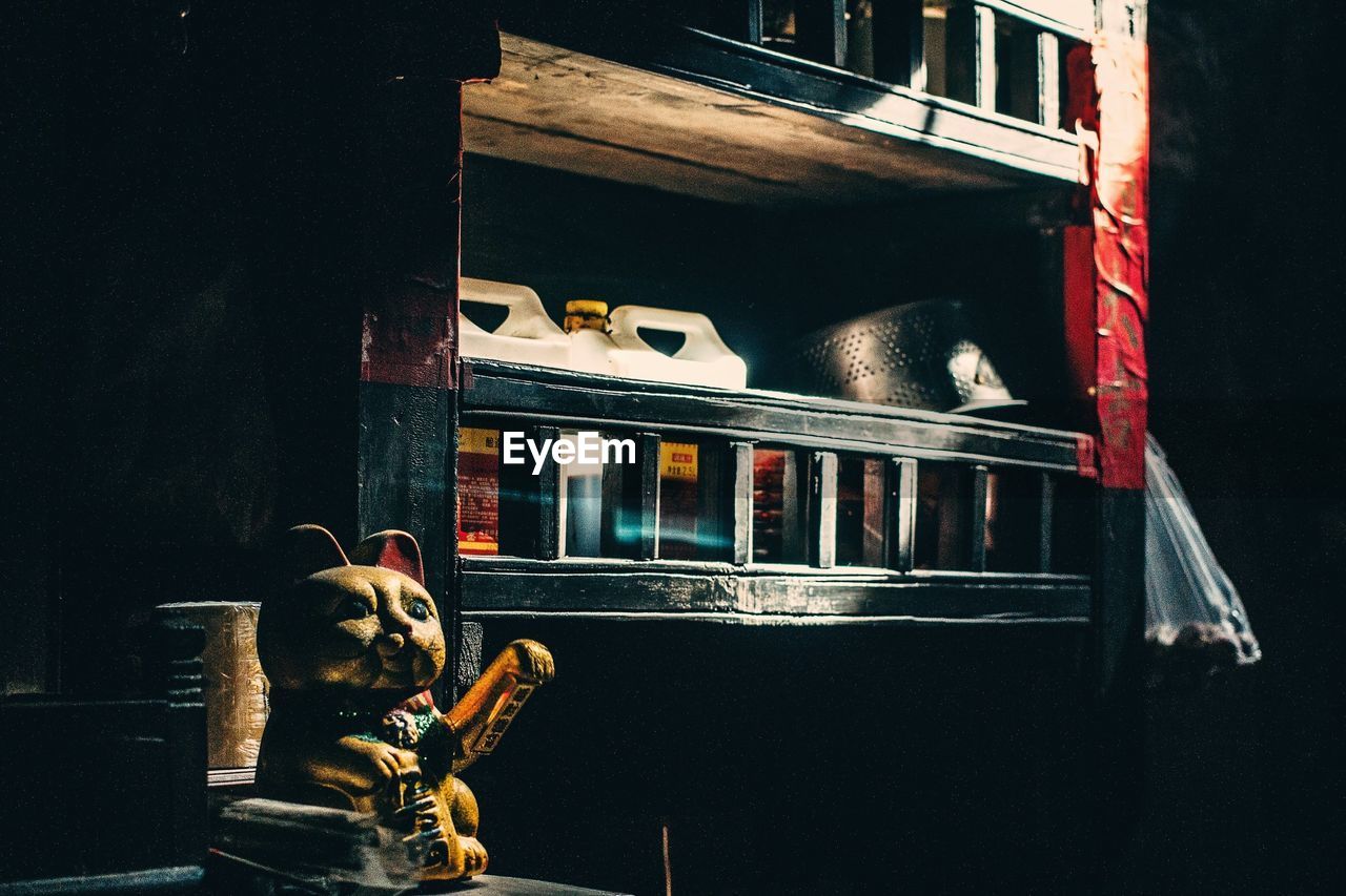 Maneki neko on table against shelf at home