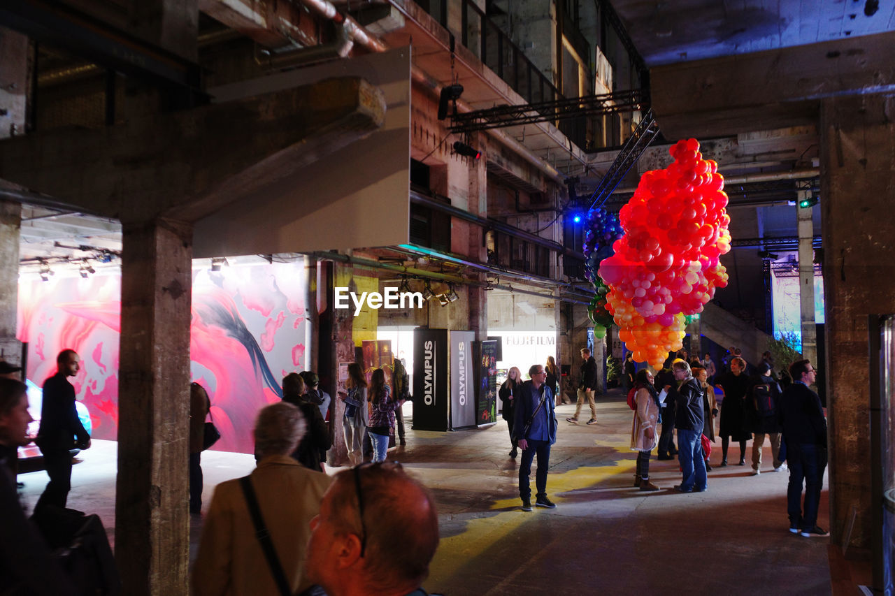 PEOPLE WALKING ON ILLUMINATED STREET