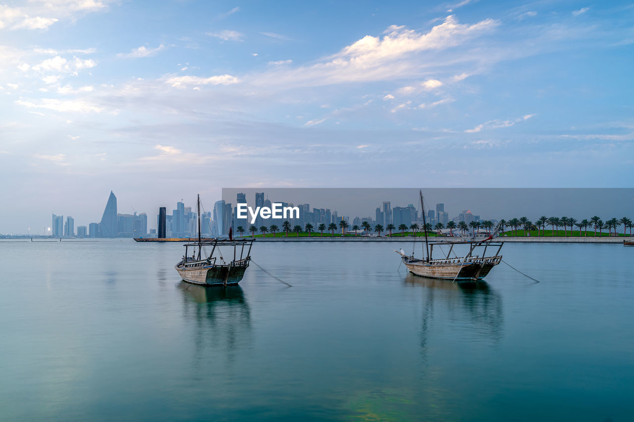 Doha skyline seen from mia park and three dhow boats in the foreground.