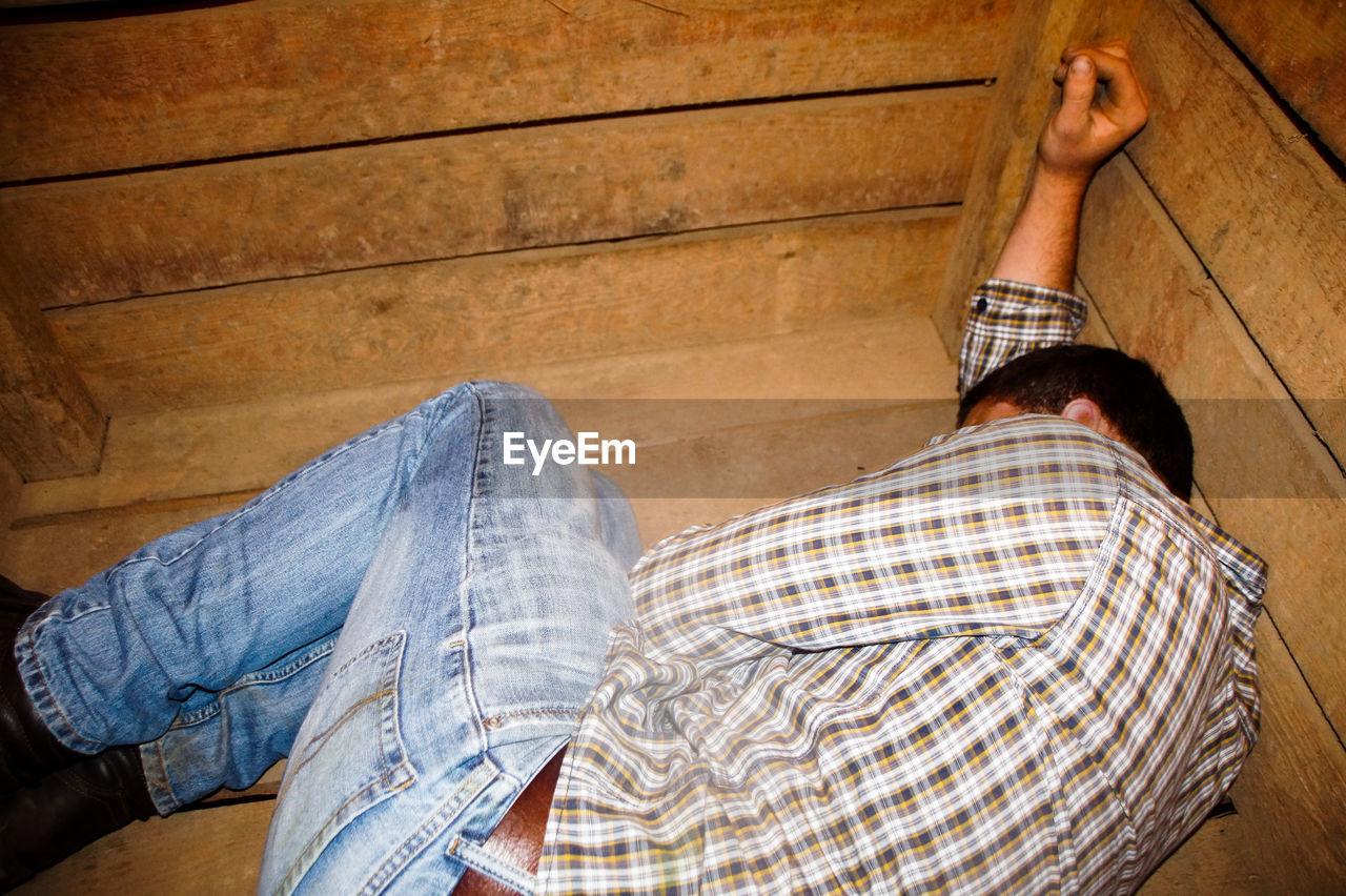 High angle view of young man sleeping on wooden floor