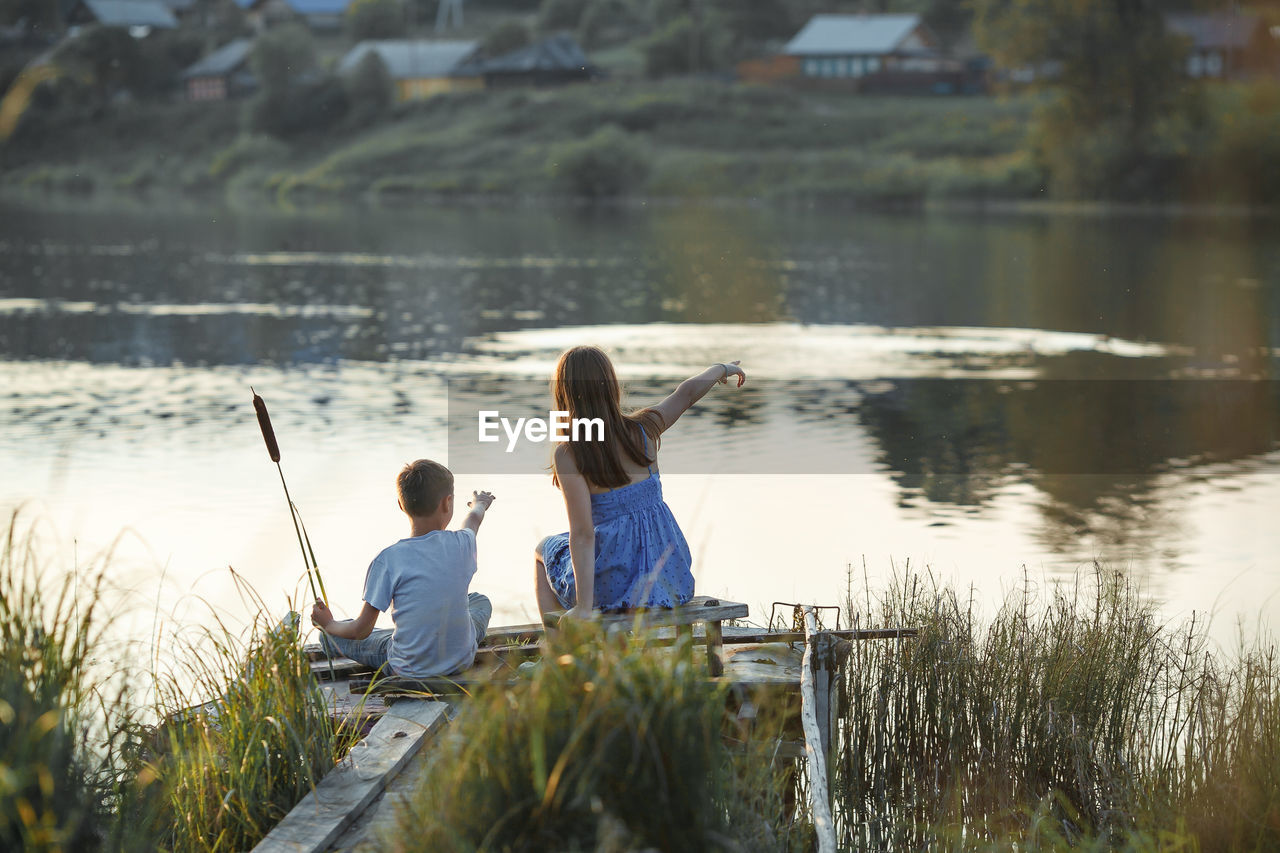 Rear view of girl and by sitting by river