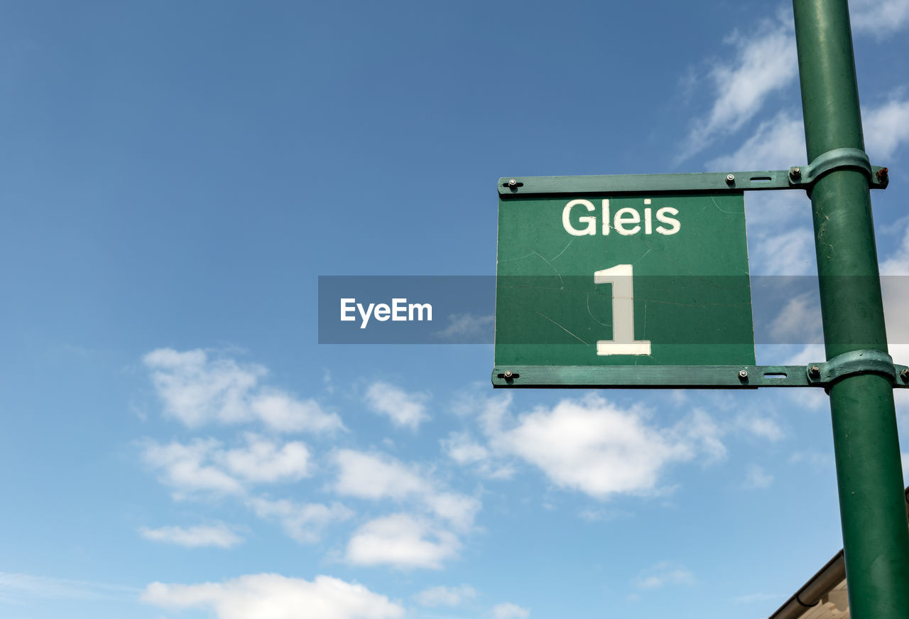 Low angle view of road sign against blue sky