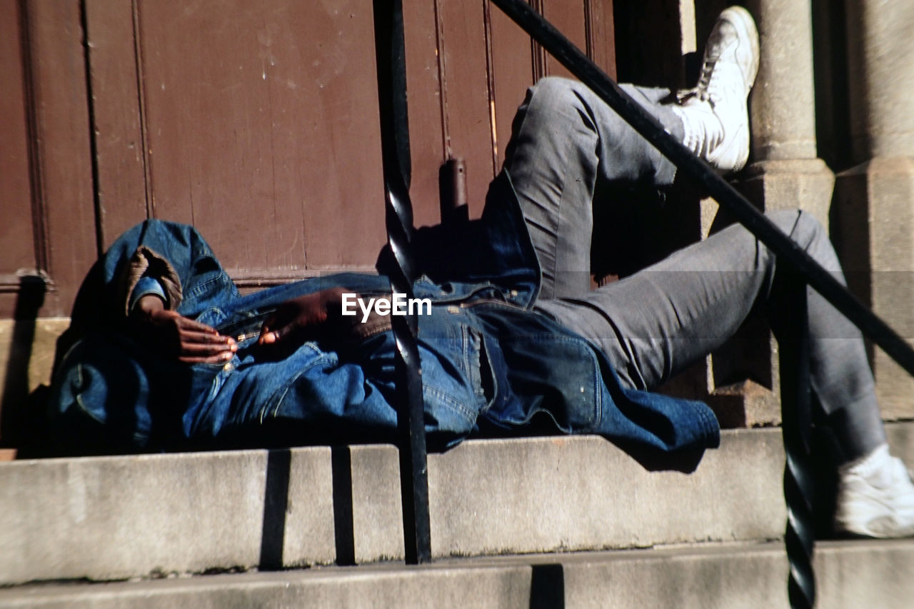 Side view of man lying on steps in city