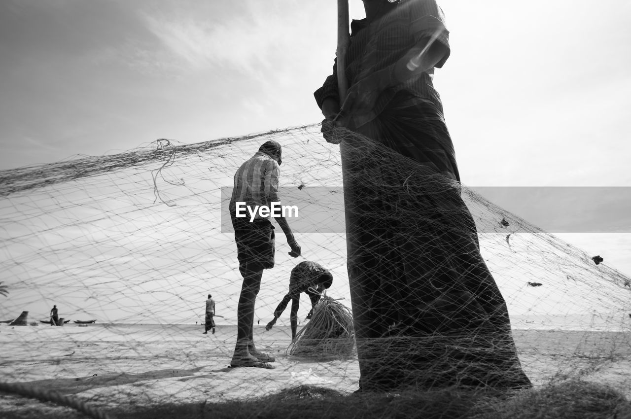 Low section of fisherman holding fishing net at beach