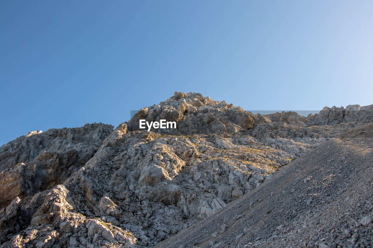 LOW ANGLE VIEW OF ROCKS AGAINST CLEAR BLUE SKY