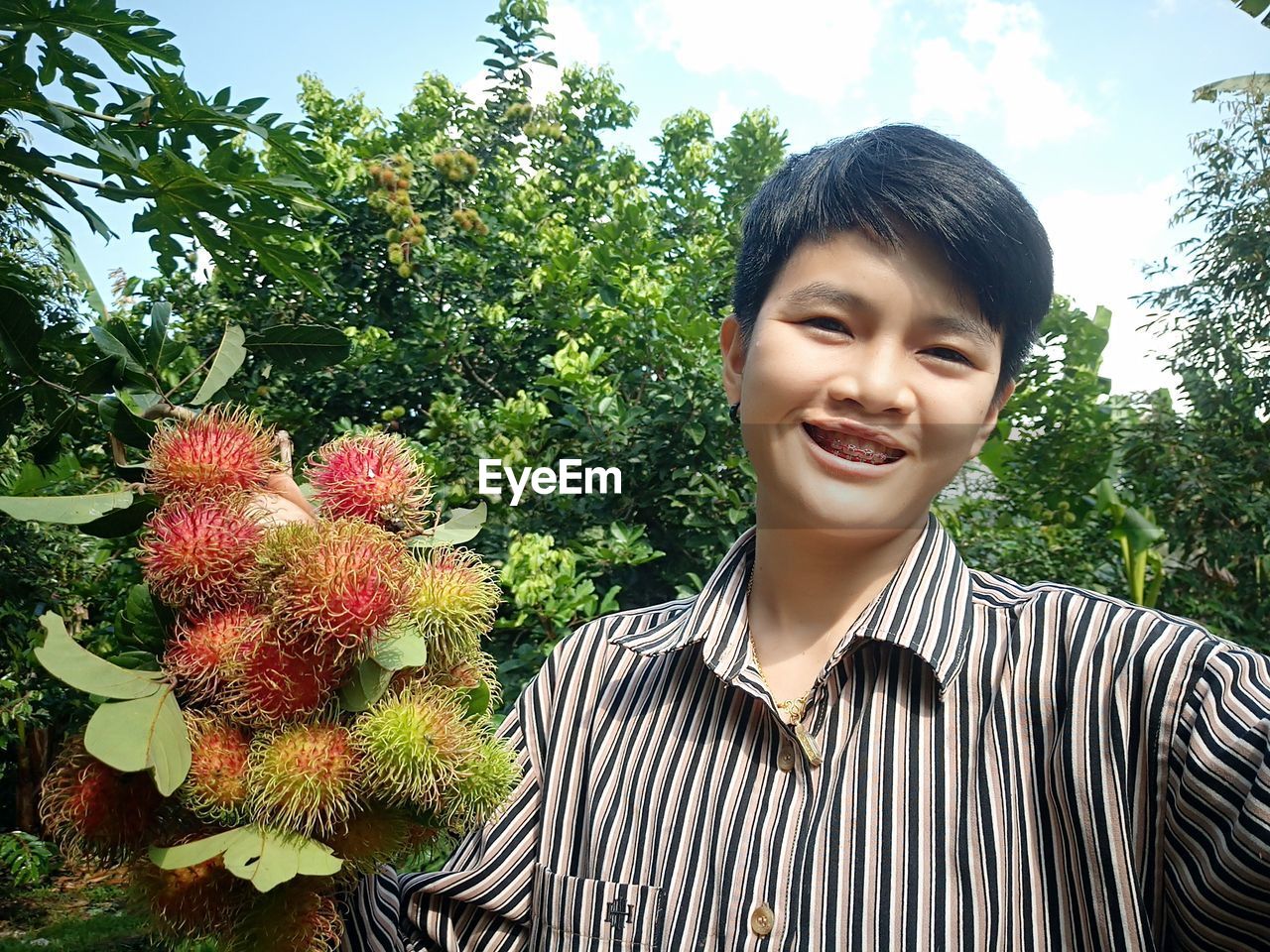 Portrait of smiling young woman holding rambutans