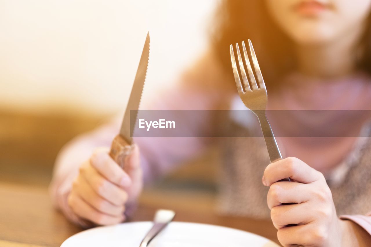 Midsection of woman with table knife and fork