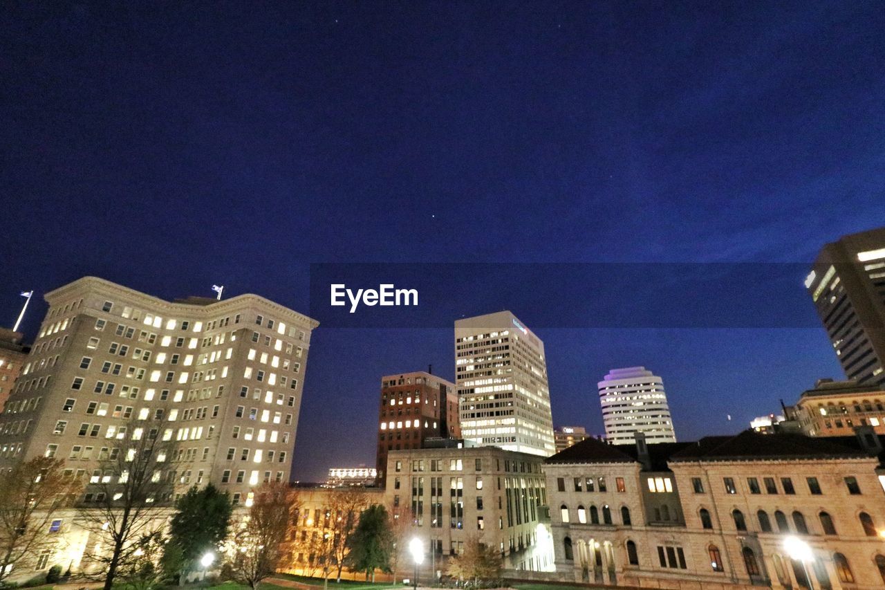 LOW ANGLE VIEW OF ILLUMINATED CITY AT NIGHT