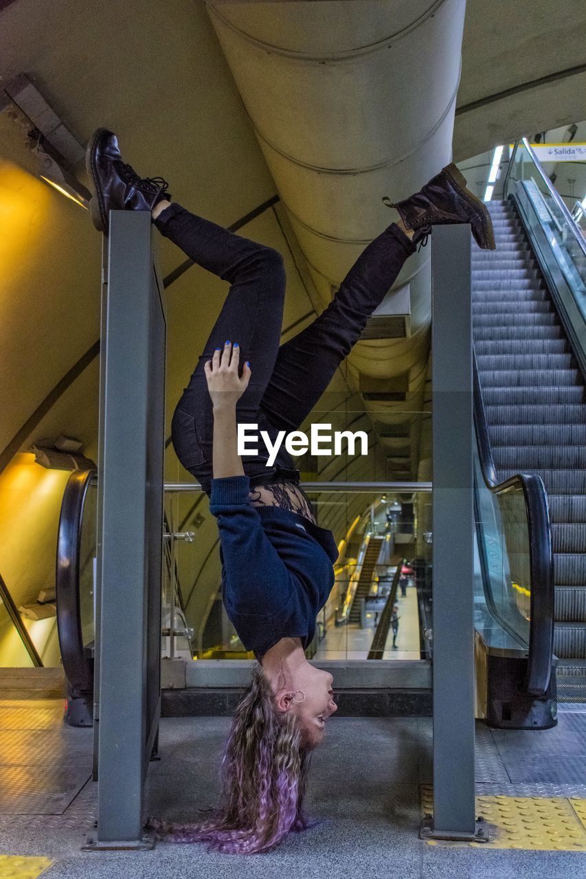 Side view full length of woman doing stunt at railroad station