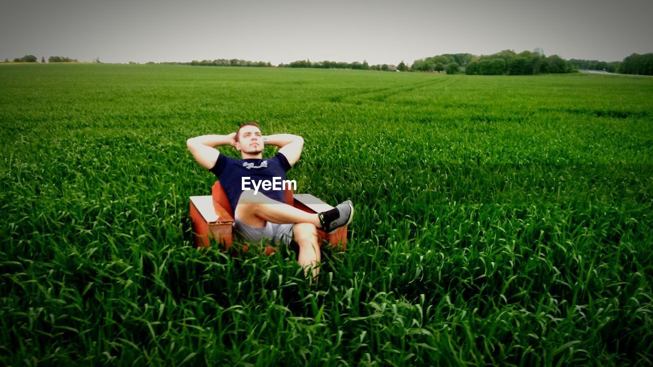 Man sitting in sofa in field