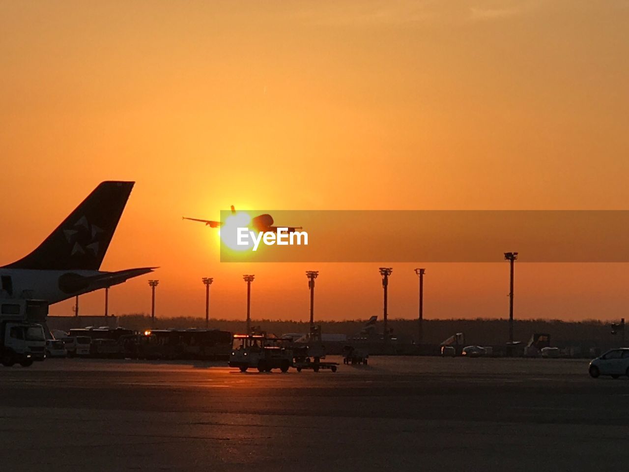 AIRPLANE ON AIRPORT RUNWAY AGAINST ORANGE SKY