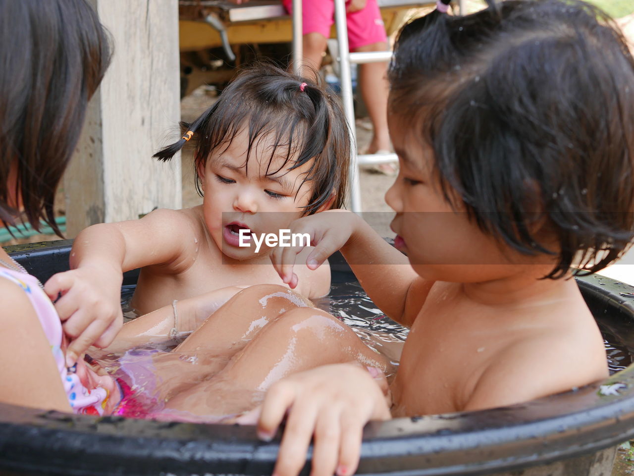 Cute girls enjoying bathing in bucket