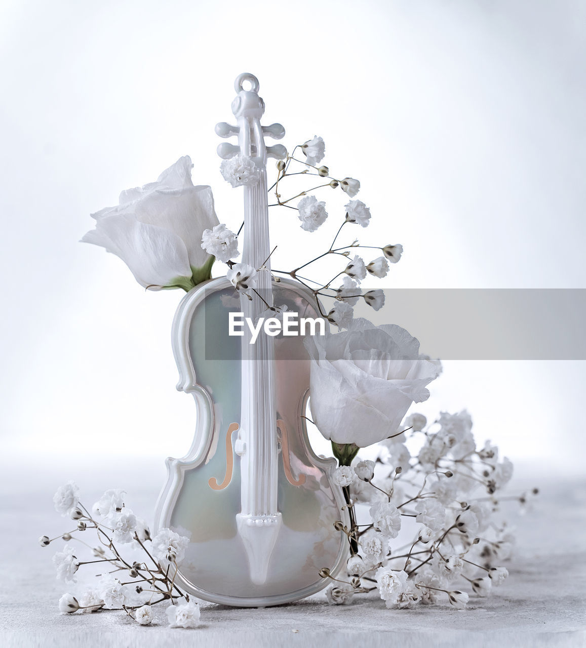 Delicate composition with artificial violin and white flower buds