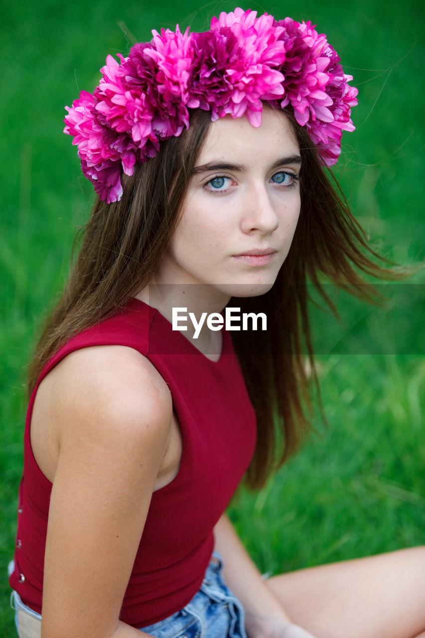 PORTRAIT OF A BEAUTIFUL YOUNG WOMAN WITH RED FLOWER