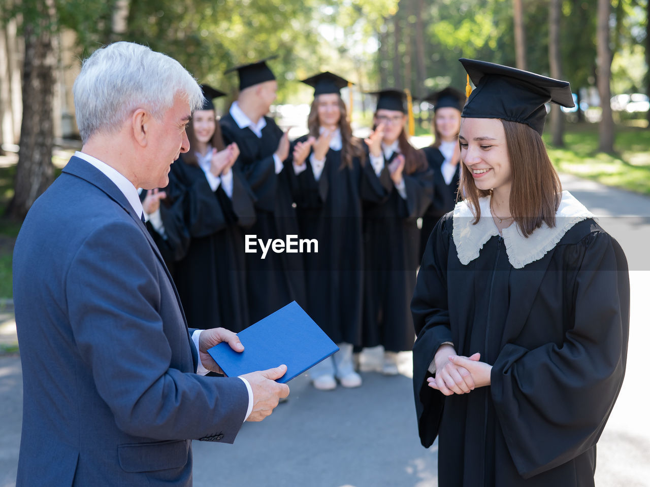 rear view of man wearing graduation gown standing in park